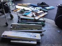Wide view of all golf training equipment spread on the ground and stacked, showing various packaged and unpackaged items including rods, boxes, and training bars.