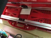 Open red carrying case with golf alignment sticks and training aids inside, items arranged for storage