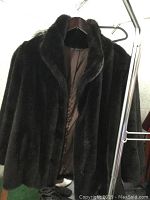 Black faux mink fur coat on hanger showing full front with collar and lined interior.