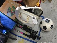 Photo showing white bowling ball bag, soccer ball, golf game box, and golf sticks.