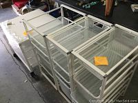 Set of four metal mesh storage organizers shown side by side revealing the mesh drawers and metal frame structure with casters.