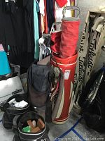 Photo showing a red and beige golf bag with golf clubs and a black golf bag.