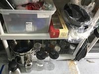 Photo showing plastic water bottles, tumblers, glass jars, thermos, measuring cups, and shelves with various kitchen items.