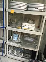 Photo showing shelving unit with white plastic turntables stacked on top shelf, clear plastic drawer organizers and dividers on second shelf, white wire baskets and a divider on the lower shelves.