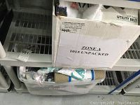 Box with assorted golf towels and golf training aids in plastic bin.