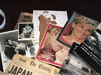 Photo showing vintage magazines, newspapers, black and white photos, and printed memorabilia spread out on surface.