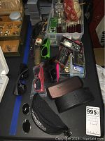 Overview of assorted sunglasses, cases, empty perfume bottles, and keychains on a table.