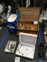 Box of assorted costume jewelry items and a Blitz jewelry cleaning machine in its box.