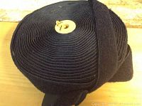 Wide view of tightly rolled navy blue Velcro tape, showing thickness and navy color.