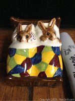 Front view of ceramic Bunnykins Sleepy Time figurine depicting two bunnies in bed under a colorful quilt.