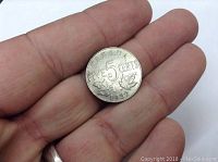 Photo of obverse side showing 'FIVE 5 CENTS', date 1932, and maple leaf design, held in hand for scale.