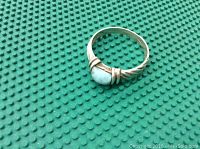 Photo of older .925 sterling silver ring with blue larimar stone on green textured background.
