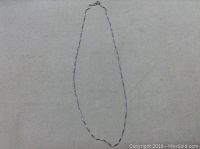 Full view of the 20 inch long silver box chain laid out to show length and design.