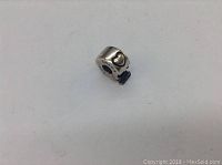 Side view of the silver charm showing black heart detail and overall shape.