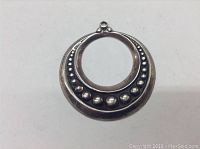 Large round sterling silver pendant with a hollow circular center and decorative silver spheres along the bottom arc, shown against a white background.