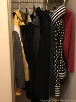 Seven assorted jackets hung on hangers in a closet, showing various colors and styles including yellow, black, red, and patterned jackets.