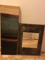 Vertical abstract print on canvas showing horizontal gradient color bands in earth tones leaning against wall.