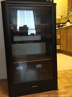 Full front view of the wood stereo cabinet with glass front door, showing its overall condition and design.