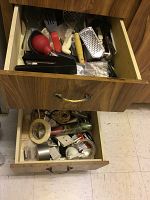 Two open wooden drawers containing assorted kitchen utensils such as baster, spatulas, whisks, graters and other tools.
