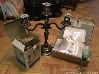 Photo showing a metal three-arm candelabra, boxed assorted colored aperitif glasses, and stationery set in transparent envelope.