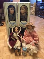 Two loose porcelain dolls dressed in elaborate outfits placed in front of boxed dolls, one holding a baby bottle accessory.