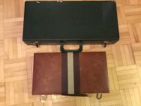 Closed view of two vintage game cases; black Mahjong case and closed brown Rummy Que game case.