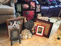 Wide view of assorted picture frames, decor items including a ceramic cow and a white flower centerpiece on a parquet floor against furniture.