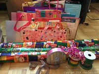 Full lot of Christmas gift wrapping paper rolls, gift bags, and cards arranged on floor