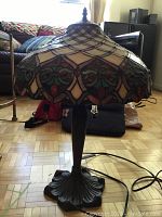 Full view of stained glass lamp showing shade and metal base on parquet floor