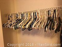 Photo shows a closet rail loaded with approximately 50 assorted plastic hangers in various colors.
