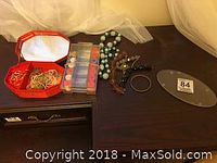 Full view of jewellery box, thread case, necklaces and bracelet laid out on dark wooden surface.