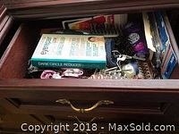 Top view of the first wooden drawer showing hairbrush, dark circle reducer box, hair clips, and scrunchies mixed with other items.