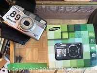 Photo showing Minolta film camera alongside Samsung camera box.