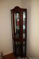 Full view of the dark wood two piece corner china cabinet with glass shelves and doors.
