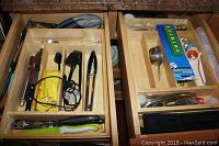 Top-down view of two wooden kitchen drawers filled with assorted kitchen utensils and flatware organized in compartments.