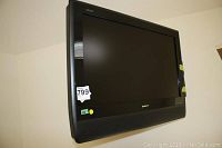 Sharp 32-inch flat screen TV mounted on the wall, black with screen off, visible wall mount bracket.