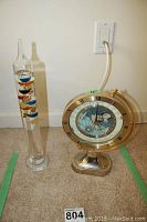 Photo of Galileo thermometer and Seiko globe style world clock together, showing size and condition.