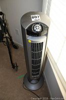 Full tower fan showing 42 inch height, grey tower design, placed indoors near window.