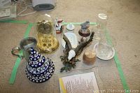 Overview of the lot including anniversary clock, ceramic doves keepsake box, bald eagle figurine, glass vase, wooden puzzle box, and small ceramic figurines