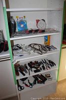 Full shelf view showing multiple shelves with hand tools, extension cords, power strip, batteries, and CD-R discs.