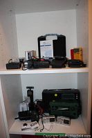 Shelf holding assorted electronics including voice recorders, radios, and accessories