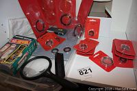 Collection of Air-Tite coin holders, packaged and loose, with magnifying glasses and a box of coin wrappers on a white surface.