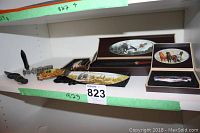 Shelf display showing multiple knives including folding knives with animal artwork and wooden display box with wildlife scene lid.