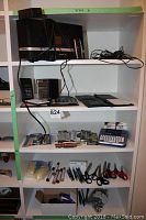 Shelf showing SiriusXM radio unit, black remote, calculators, and office supplies including scissors and pens.
