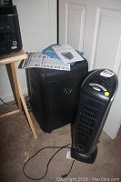 Amazon Basics shredder beside Lasko ceramic tower heater on carpeted floor with instruction manual on shredder.