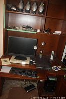 Full computer setup on wooden desk with hutch including HP Pavilion desktop under desk, Accusync monitor on top, Dell keyboard, cords, cordless phone, desk lamp, and Stamps.com scale.