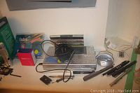 Photo showing assortment of electronics including Sangean radio, cables, power supply, MP3 player, clock and thermometer, and cleaning wipes.