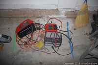 Photo shows Black & Decker Air Station AS1300 compressor and Schumacher Speed Charge battery charger with cables placed on concrete floor.