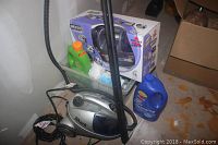 Shark Euro Pro X steam cleaner with hose, Bissell fiber cleansing formula bottle, and assorted cleaning items on basement floor