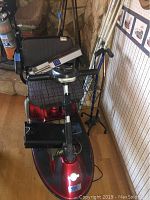 Full front-left view of red Revo mobility scooter with canes leaning behind it